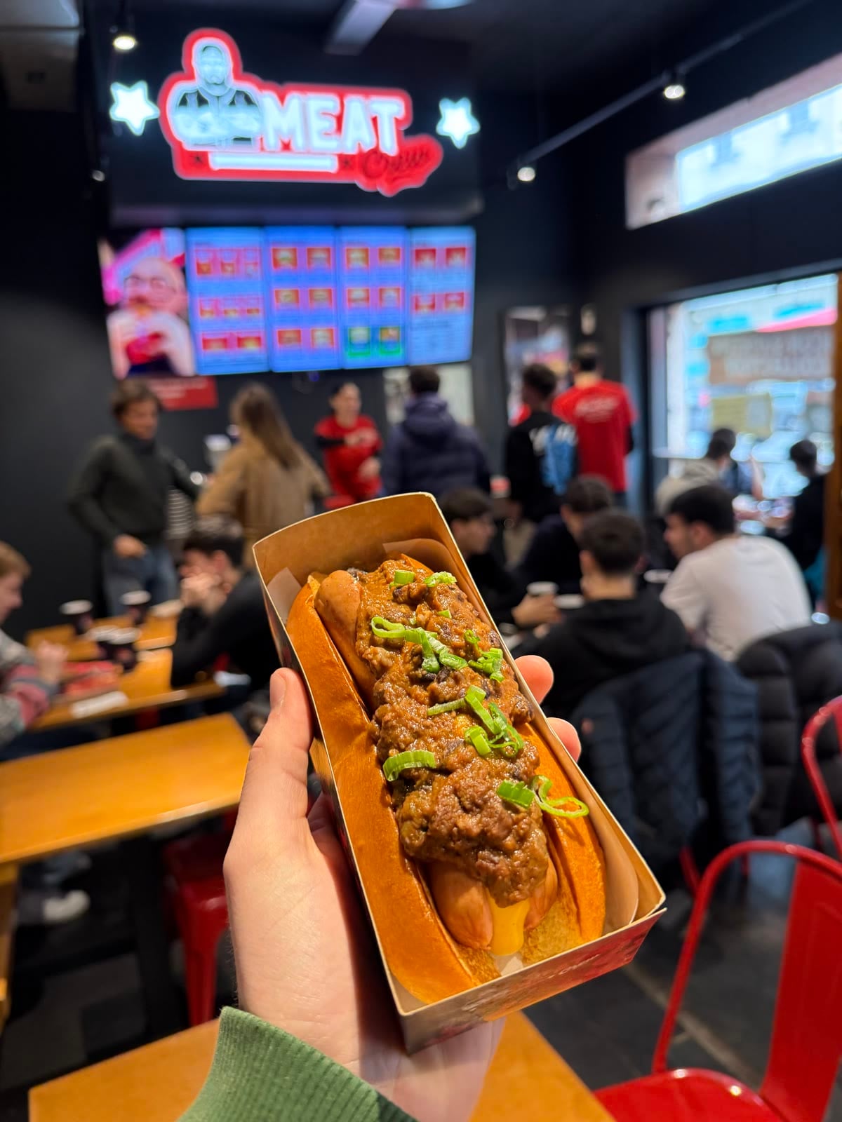 Un chili dog di Meat Crew in mano, nella sala dello store di Viale Bligny a Milano